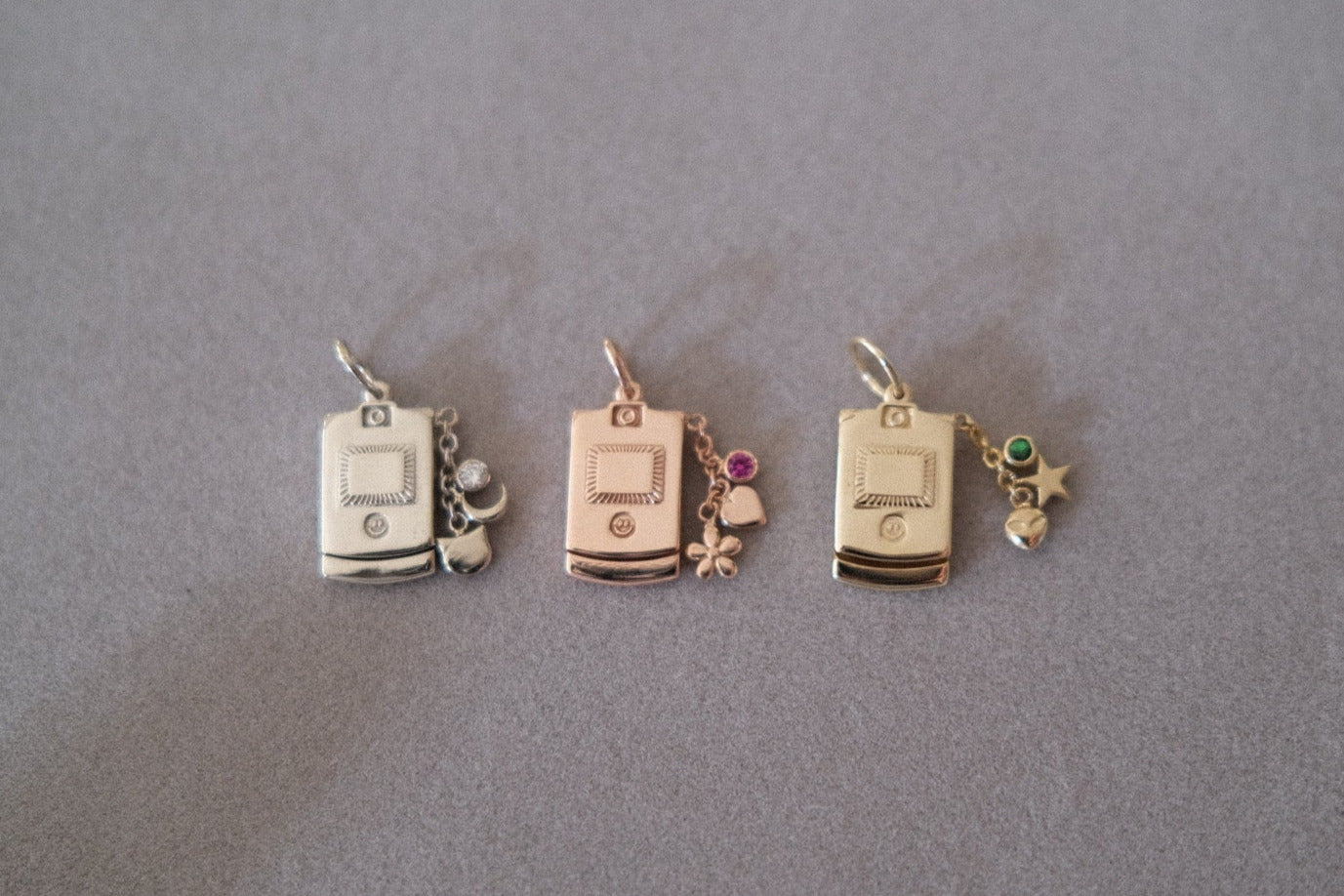 Three small jewelry charms on a gray background