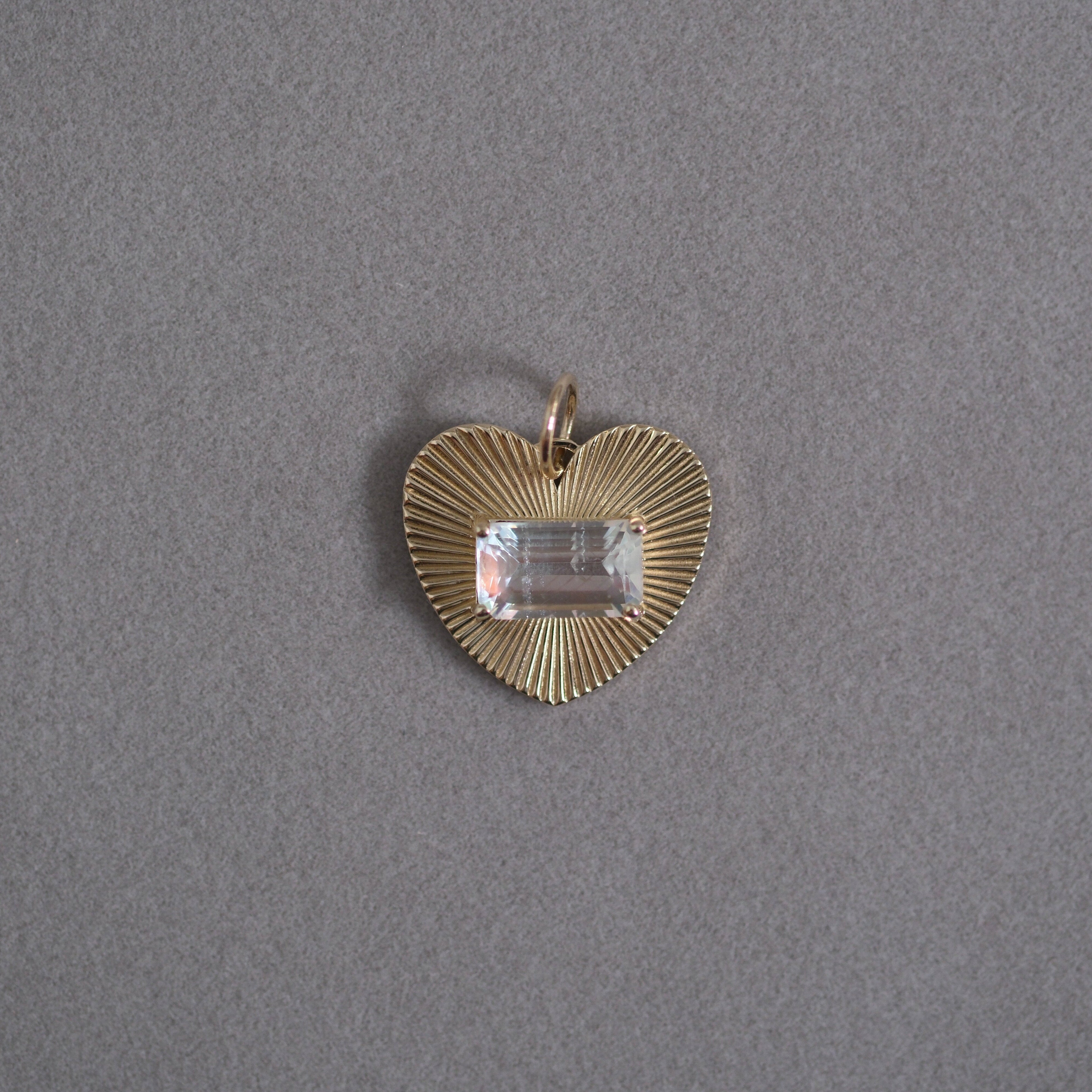 Gold heart-shaped pendant with a moonstone gemstone on a gray background